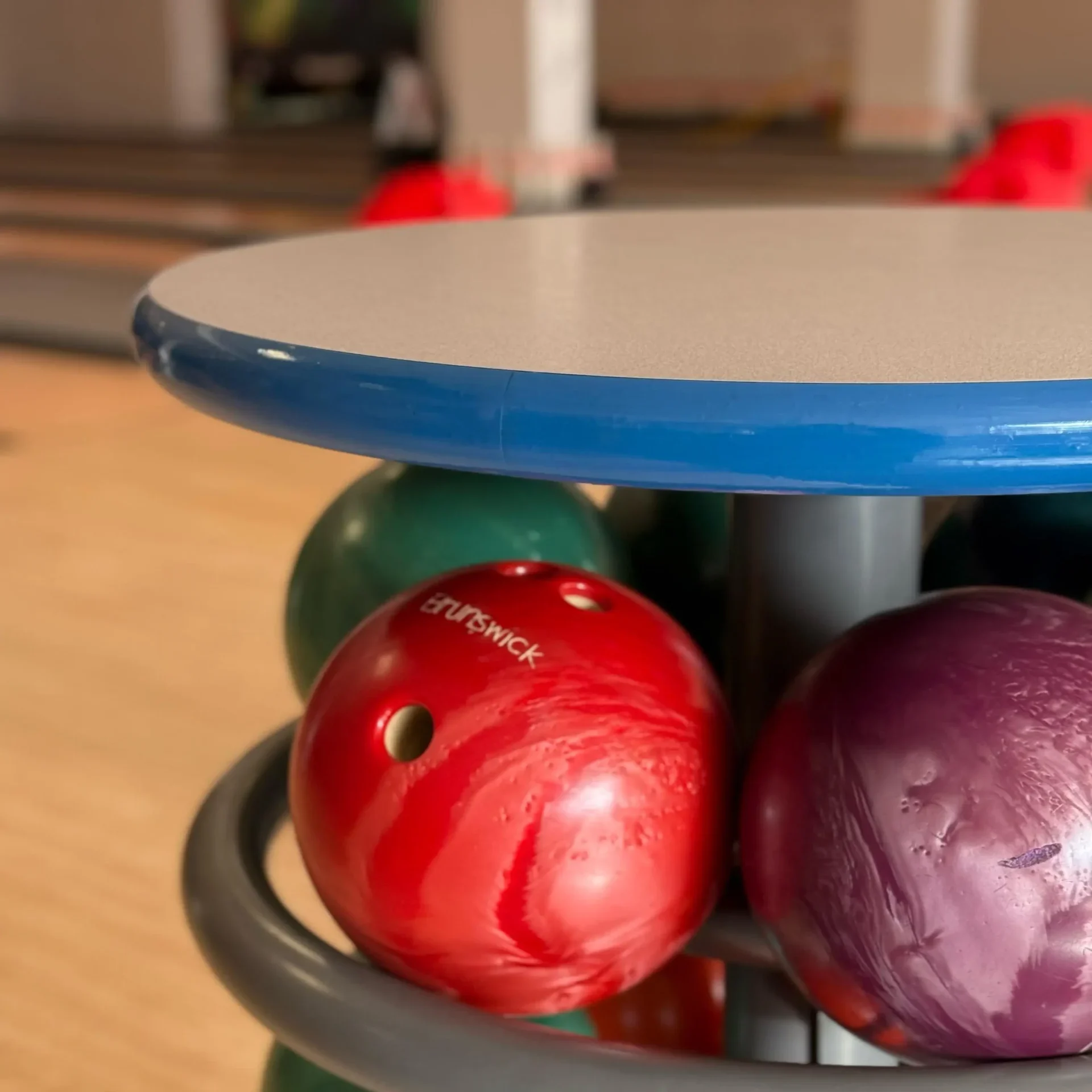 Bunte Brunswick-Bowlingkugeln im Ständer in der Nähe der Bahnen in einer Bowlinghalle